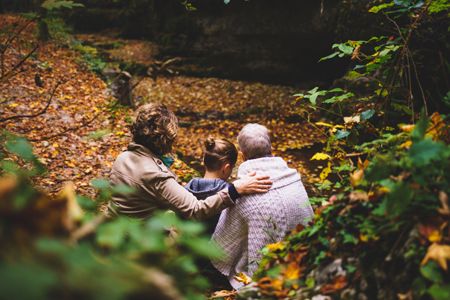 Zwei Frauen mit Kind sitzen im Wald auf Bank